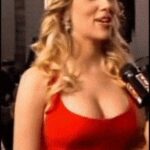 Scarlett Johansson smiling and letting a random reporter squeeze her bosom on camera